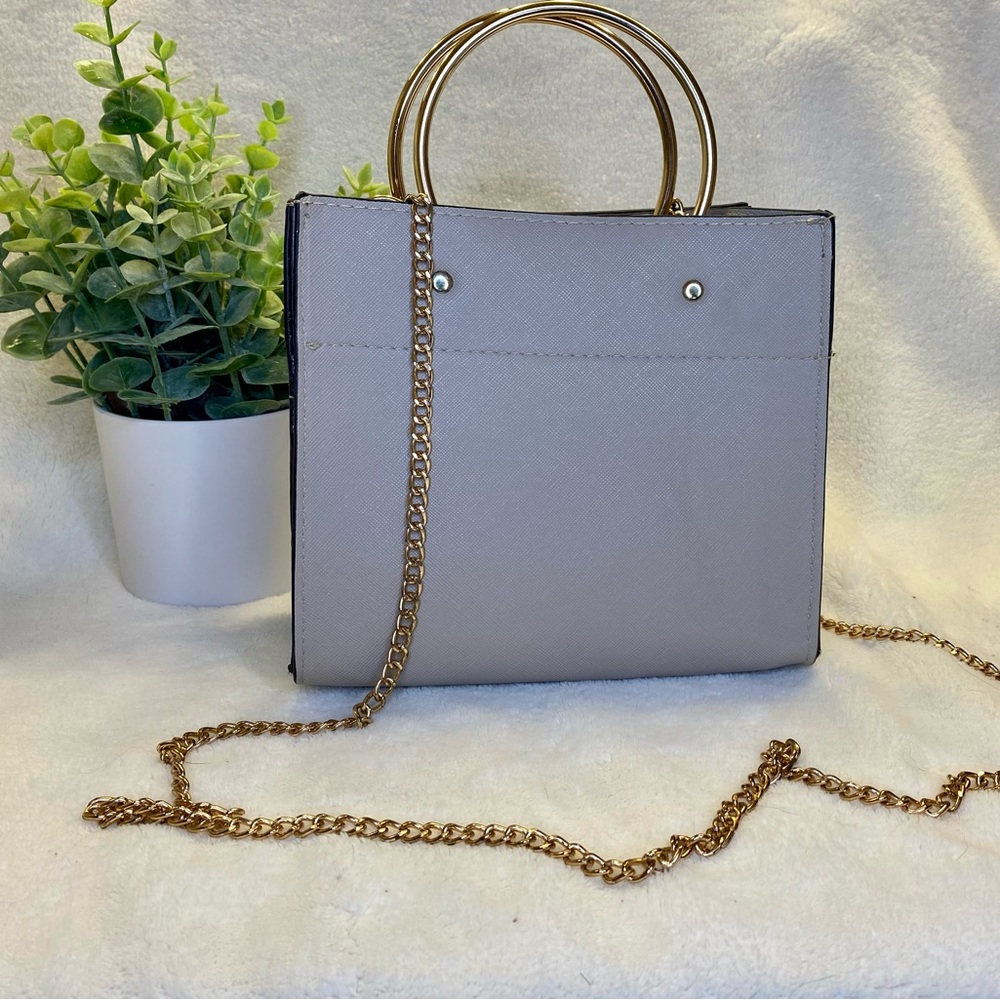 Small, tan hand bag. Gold hooped handles and gold chain shoulder strap.